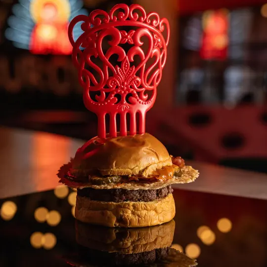 Burger sobre pan brioche dorado, coronada con una pieza roja tallada